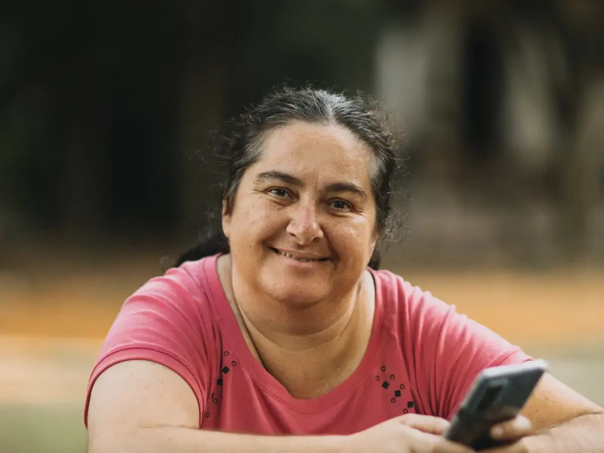 Señora sonriendo con su celular en la mano
